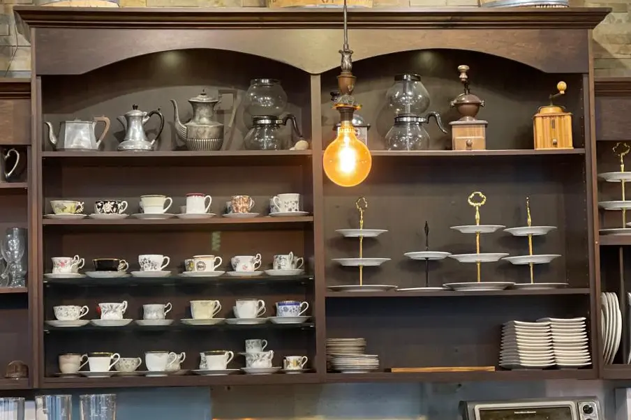 Vintage coffee cups and traditional siphon brewers displayed on wooden shelves inside La Cuisson Café in Vancouver.