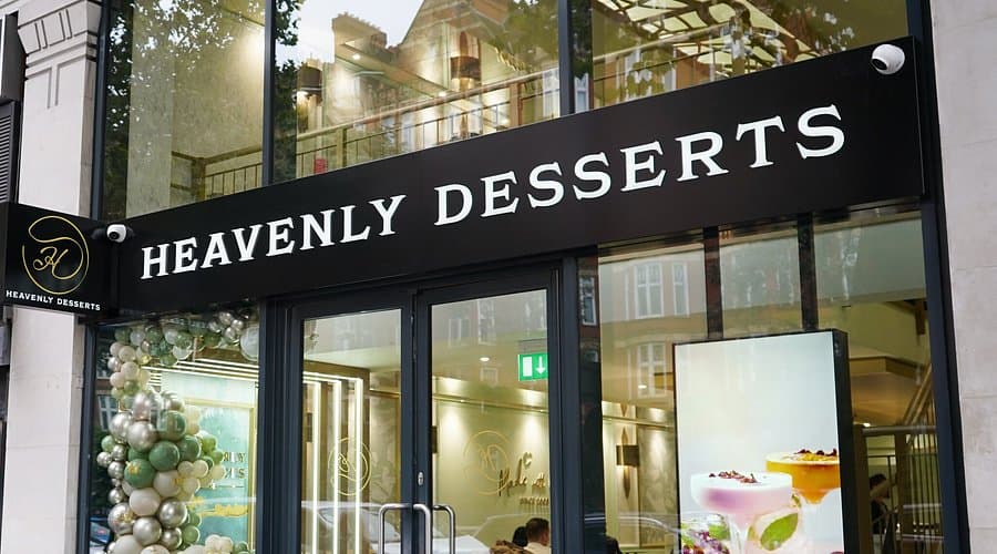 Exterior of Heavenly Desserts with a black storefront sign and large glass windows revealing a bright, modern interior.