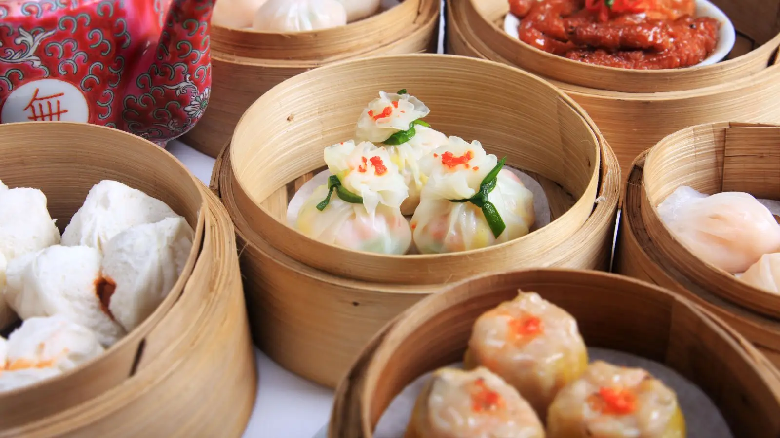 A close-up of steamed dumplings and shumai arranged inside bamboo steamers